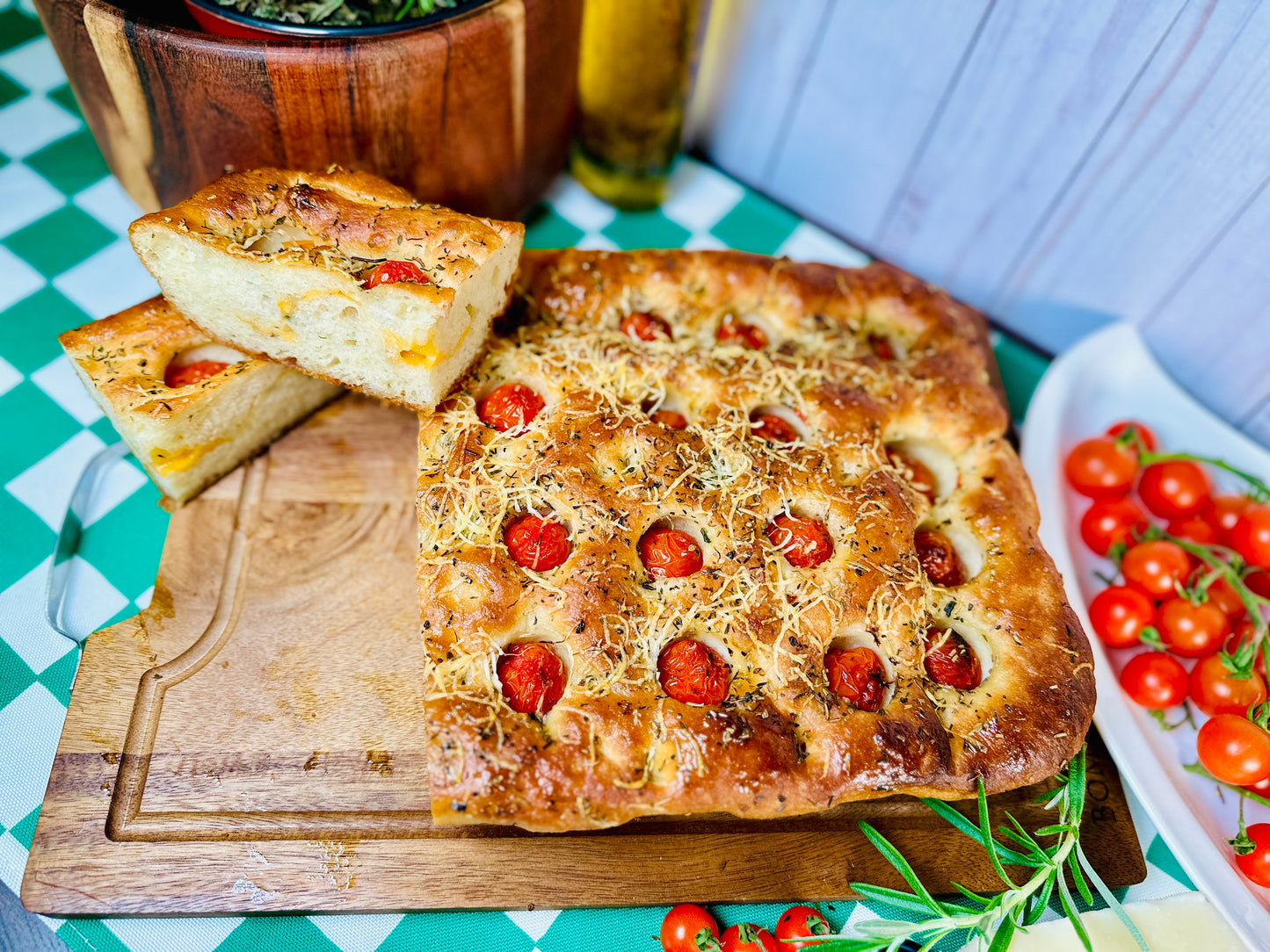 Homemade Italian focaccia bread with cherry tomatoes and herbs on a wooden board